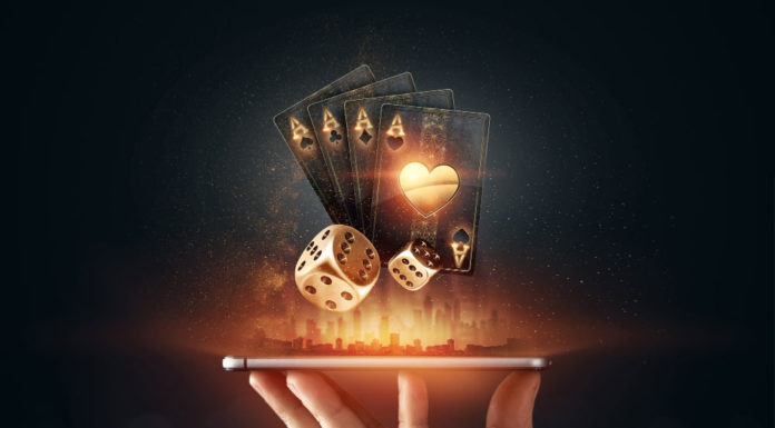 A hand holding a smartphone horizontally, from which glowing golden playing cards and dice are digitally emerging, symbolizing online gambling and casino entertainment. The background is dark with a subtle illuminated cityscape silhouette, enhancing the futuristic and dynamic feel of the image.