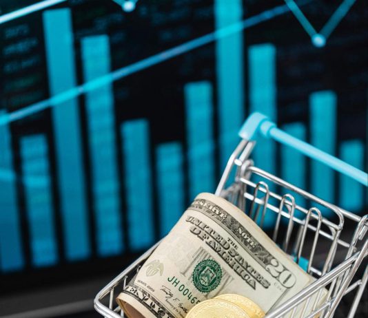 Image of cash and physical bitcoins in a tiny shopping cart